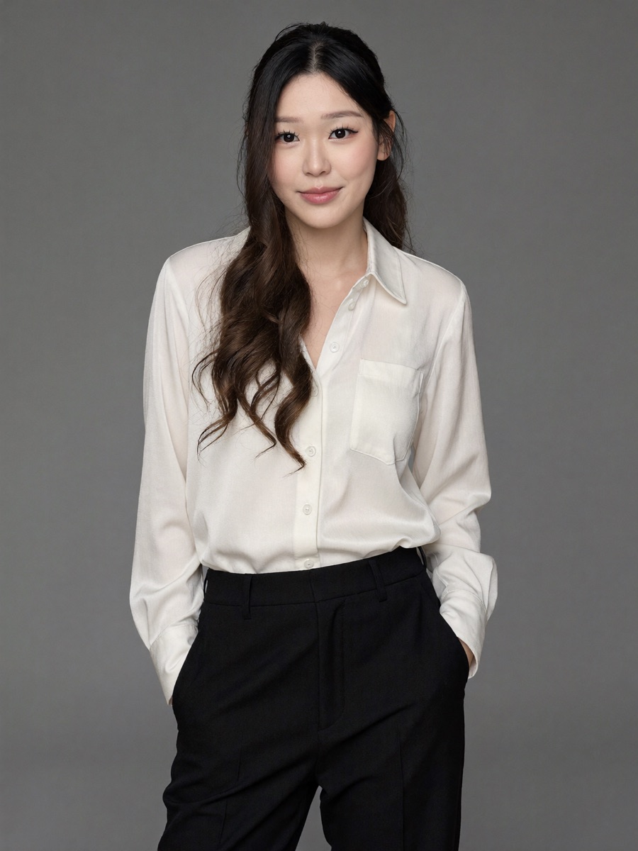 Ivory silk blouse and black trousers, hands in pockets, grey studio