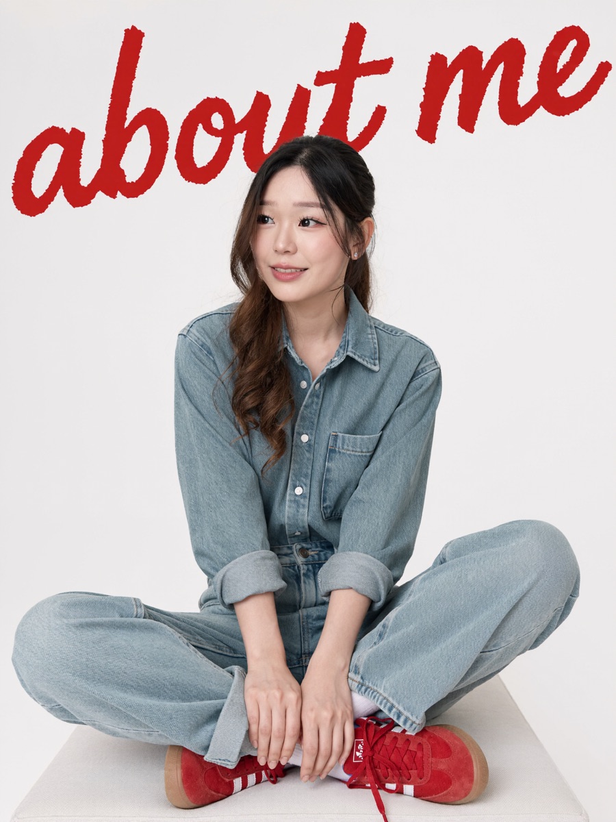 Double denim and red Adidas sneakers, seated cross-legged, big red 'about me' script in the background