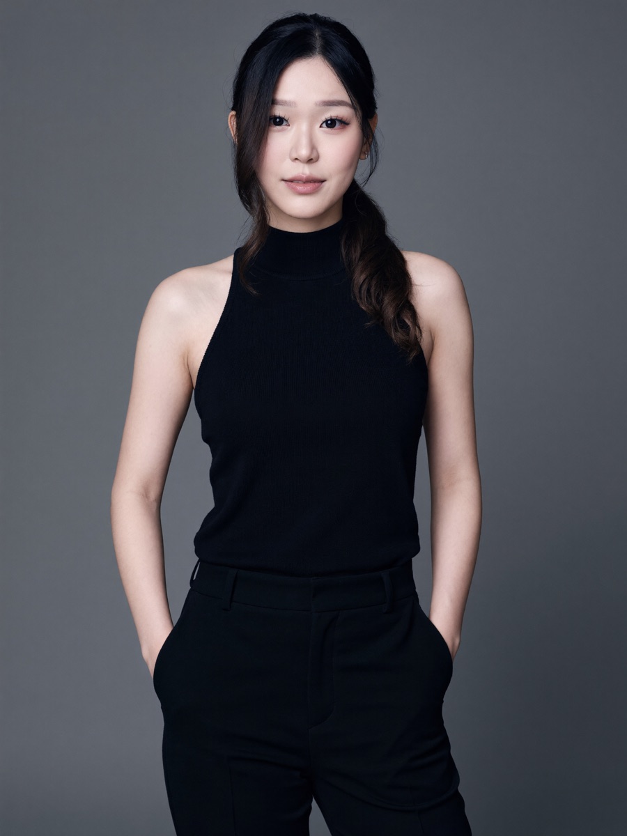 Sleeveless black knit top and trousers, low ponytail, grey studio
