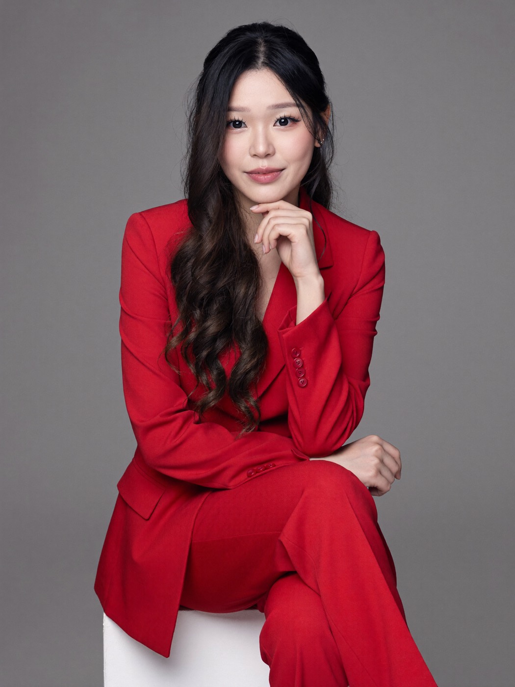 Red suit on a white cube against a grey studio backdrop