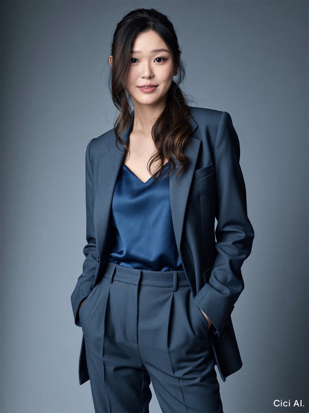 Navy suit over a blue silk camisole on a grey gradient backdrop