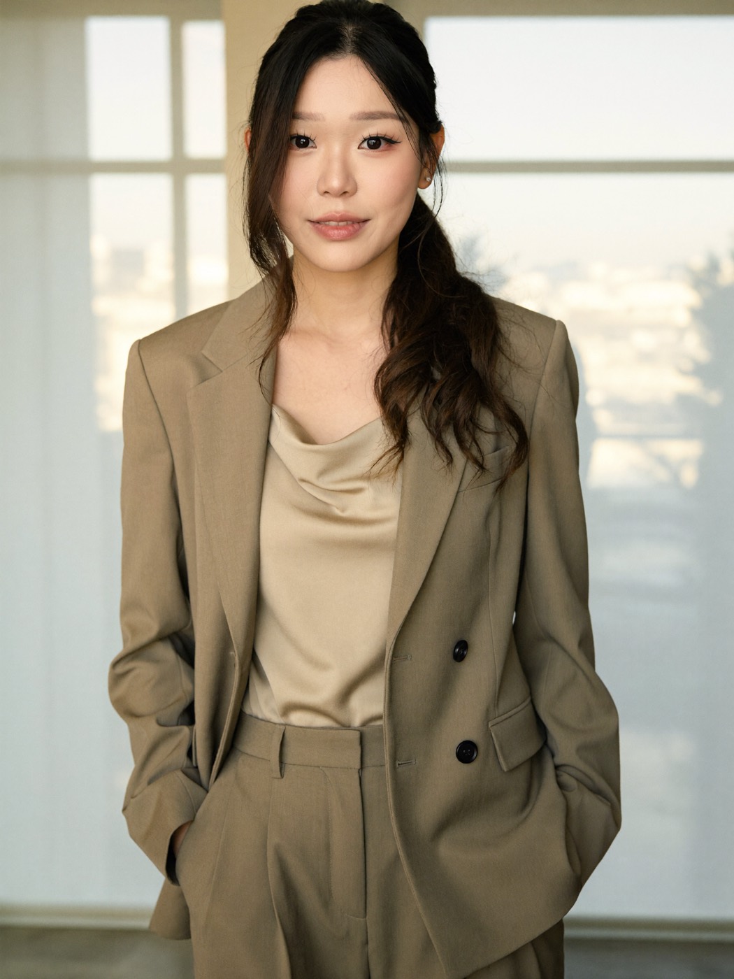 Taupe oversized suit and satin cowl neck blouse in warm window light