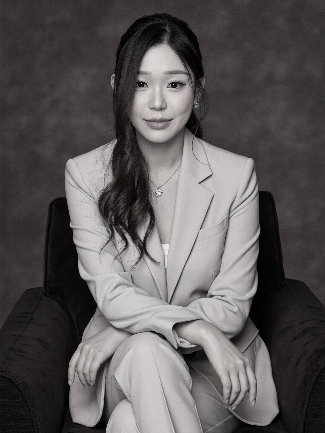 Black and white portrait in a pale suit on a dark velvet armchair